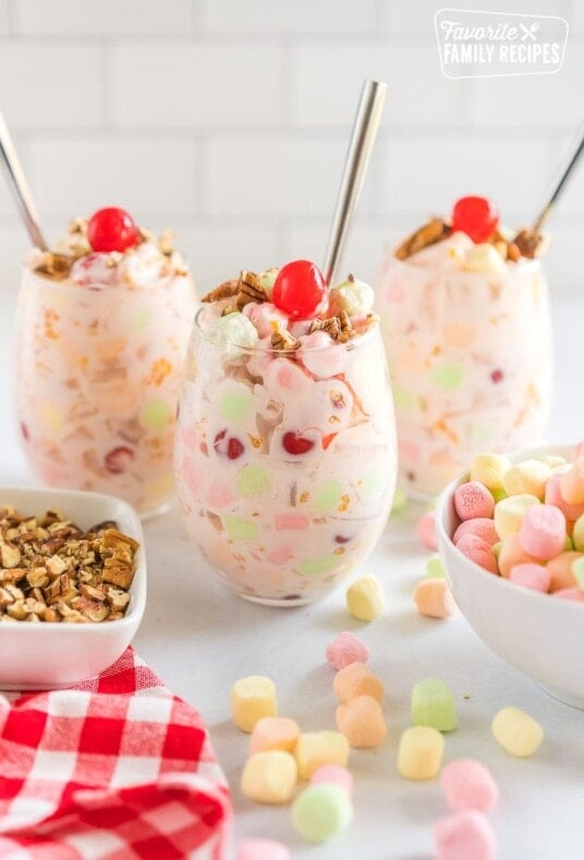 Three cups of Ambrosia salad topped with pecans and cherries