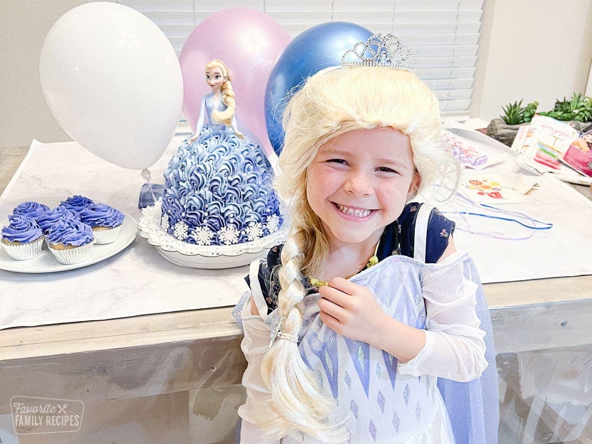 Girl next to an Elsa birthday Barbie cake