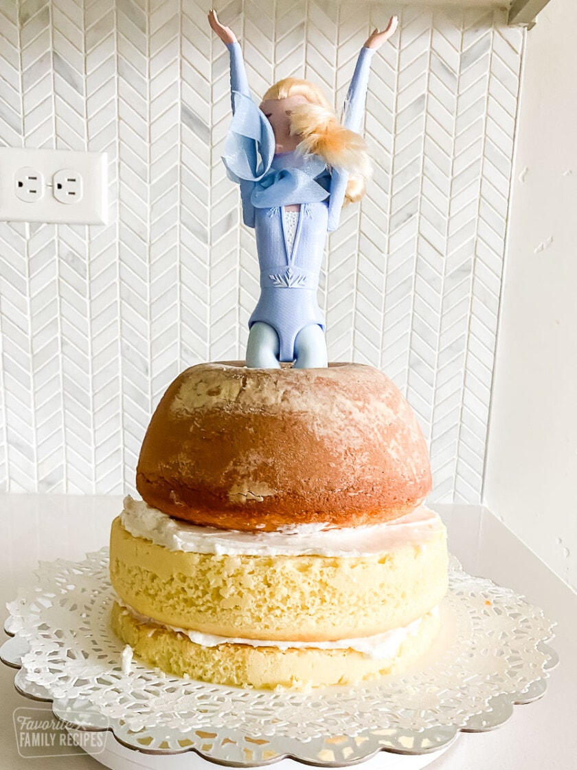 An Elsa Barbie doll sticking out of layers of cake.