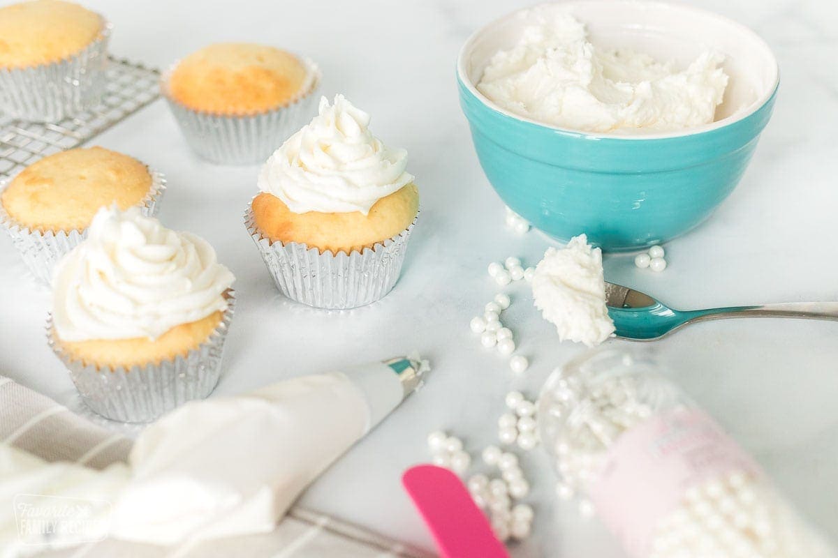 Cupcake decorating supplies next to a bowl of buttercream frosting