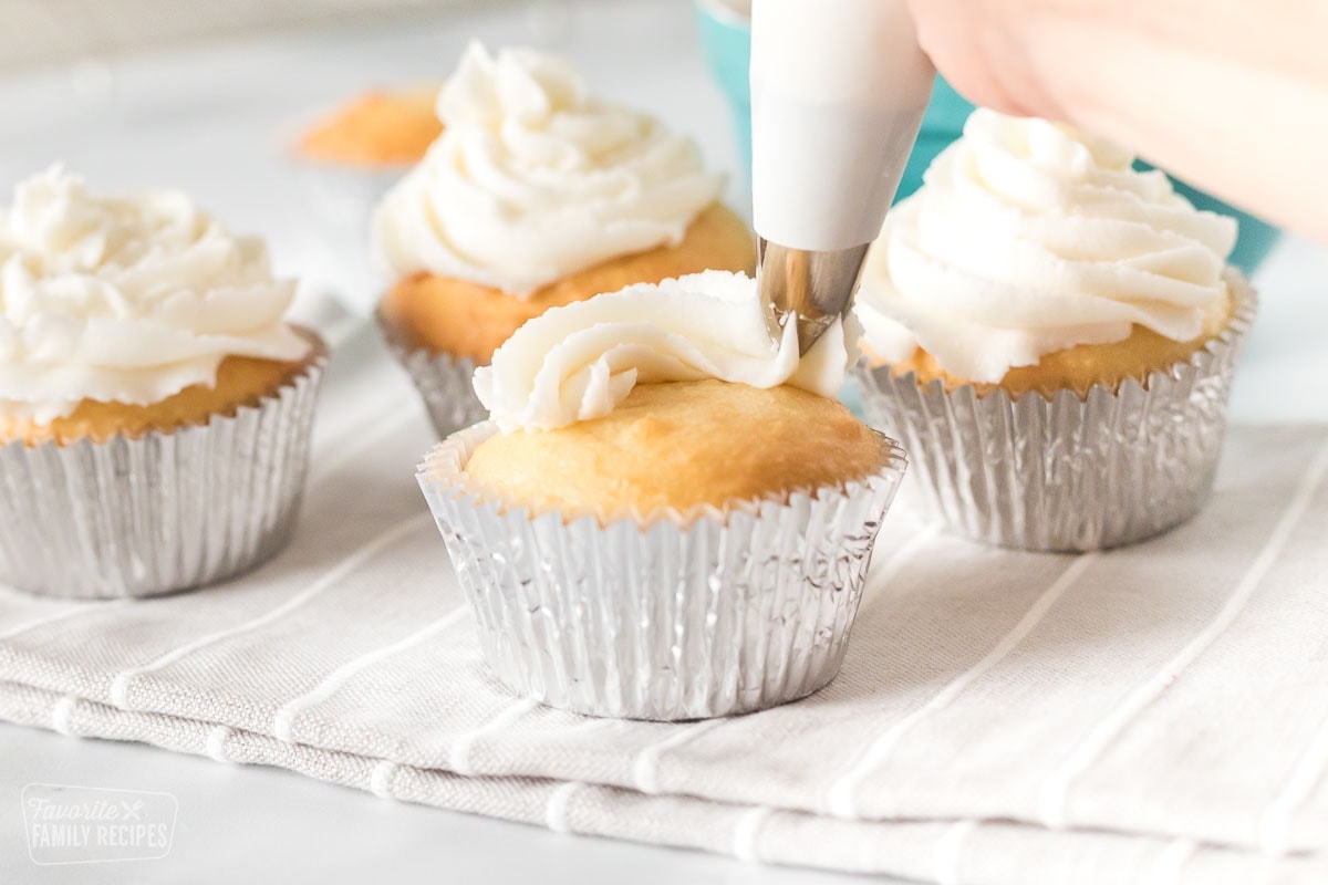 Buttercream frosting being piped onto a cupcake