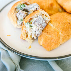 Creamy Cheesesteak Crescent rolls on a plate with one cut in half