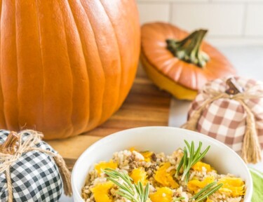 A large pumpkin filled with casserole and a bowl with casserole topped with pumpkin chunks and fresh rosemary