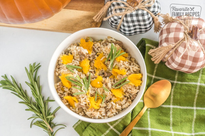A bowl of dinner in a pumpkin casserole topped with fresh rosemary