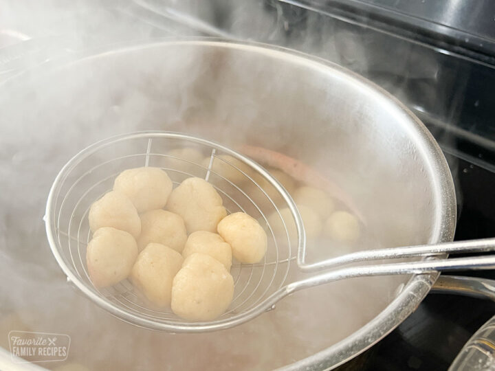 Gnocchi being scooped out of a pot of boiling water