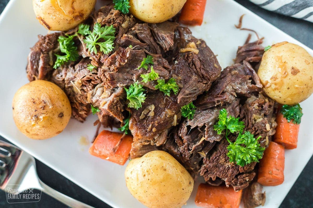 Pot roast on a plate with potatoes and carrots.