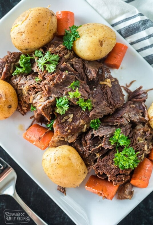 An Instant Pot pot roast on a plat with carrots and potatoes