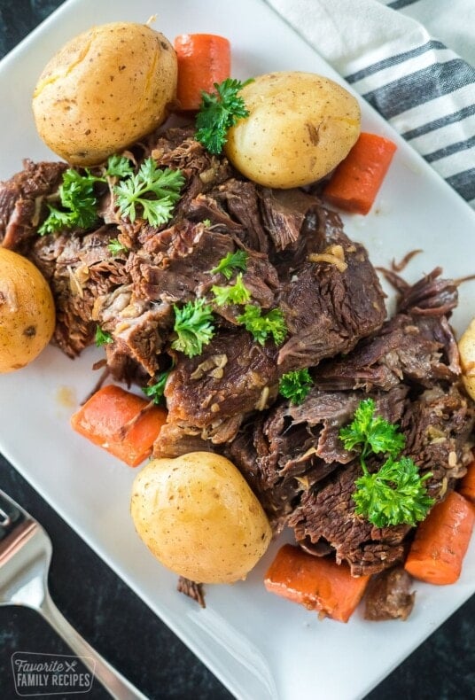 An Instant Pot pot roast on a plat with carrots and potatoes.