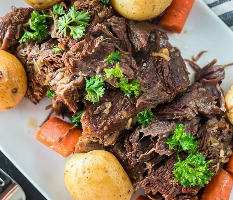 An Instant Pot pot roast on a plat with carrots and potatoes