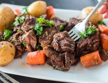 A bite of pot roast being picked up with a fork