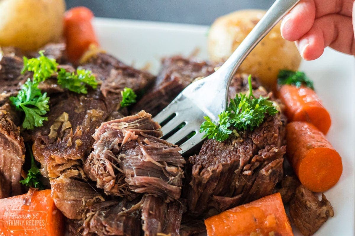 A close-up of a cut of tender pot roast on a fork.