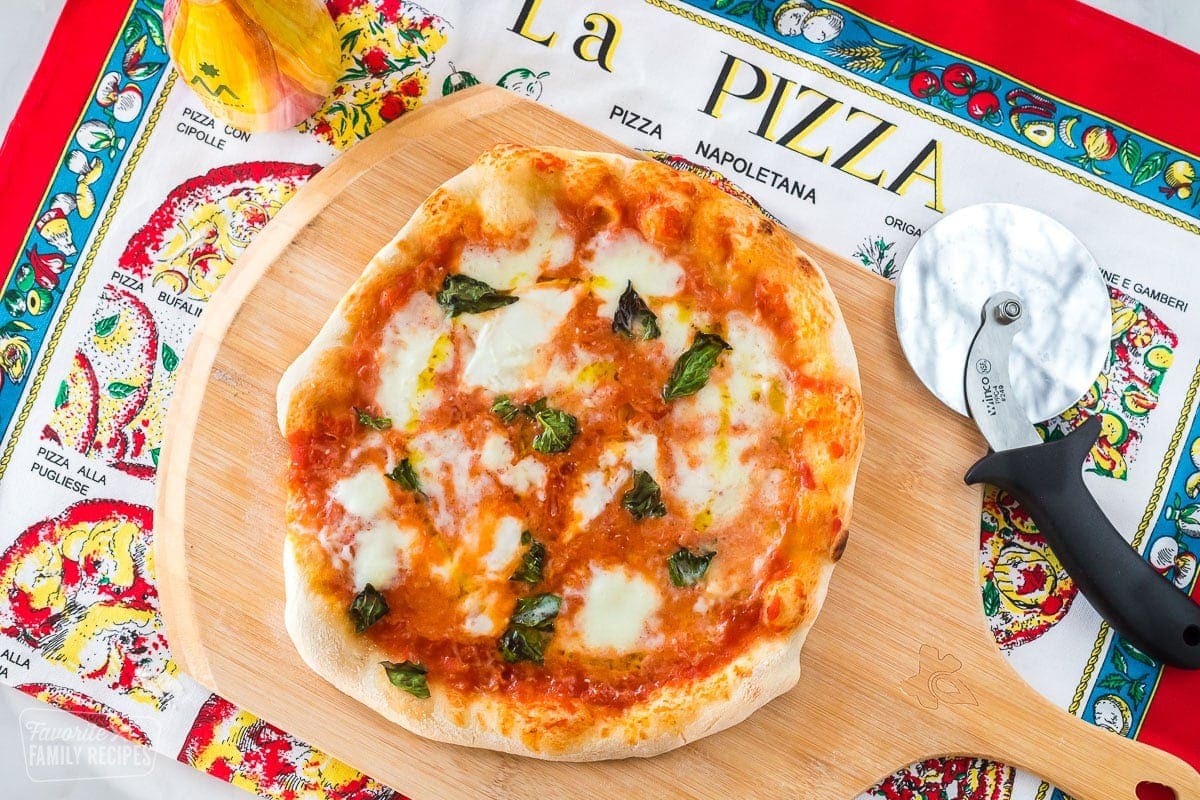 A cooked Neapolitan pizza on a wooden pizza peel.