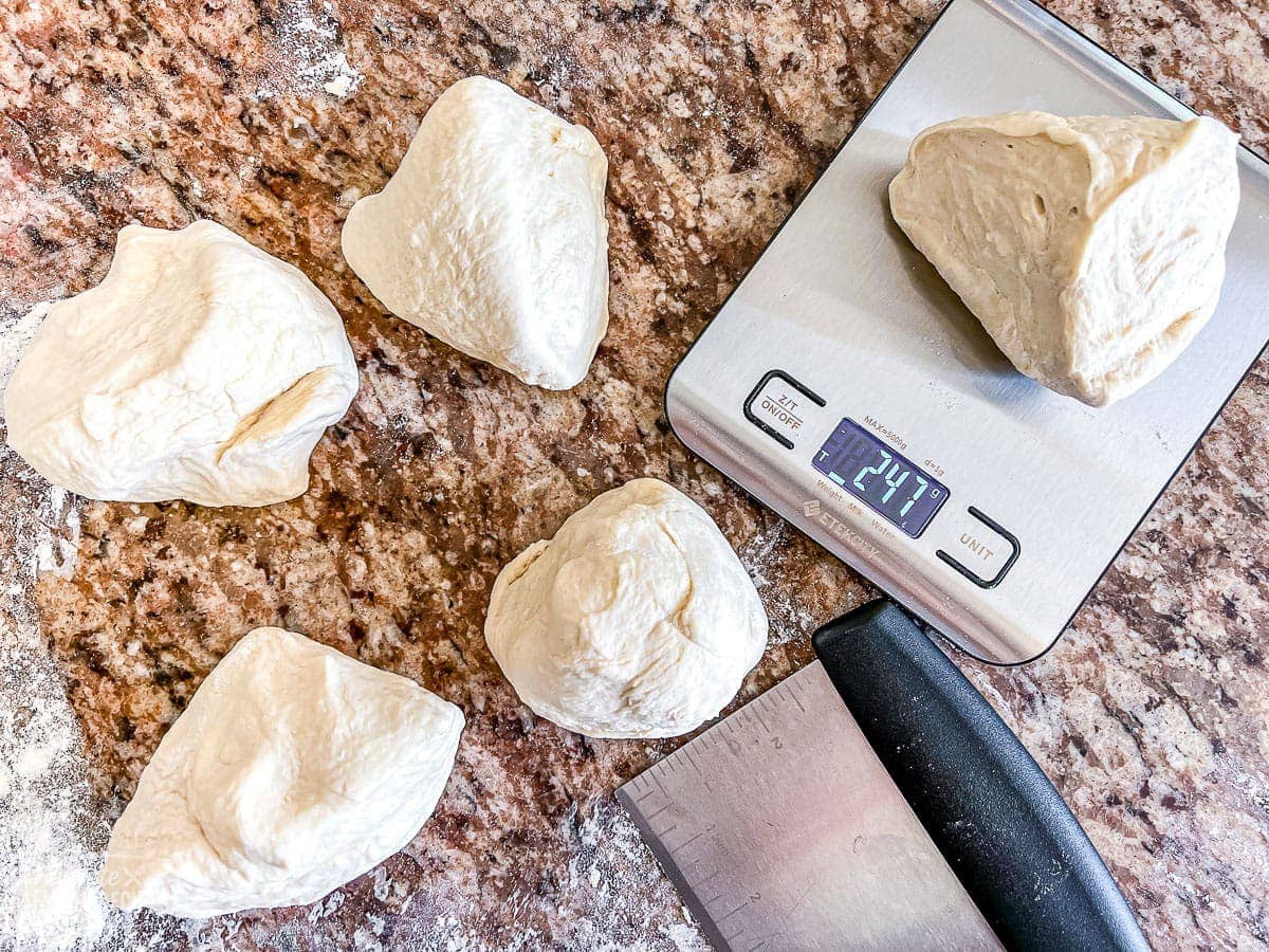 Pizza dough balls being weighed on a scale