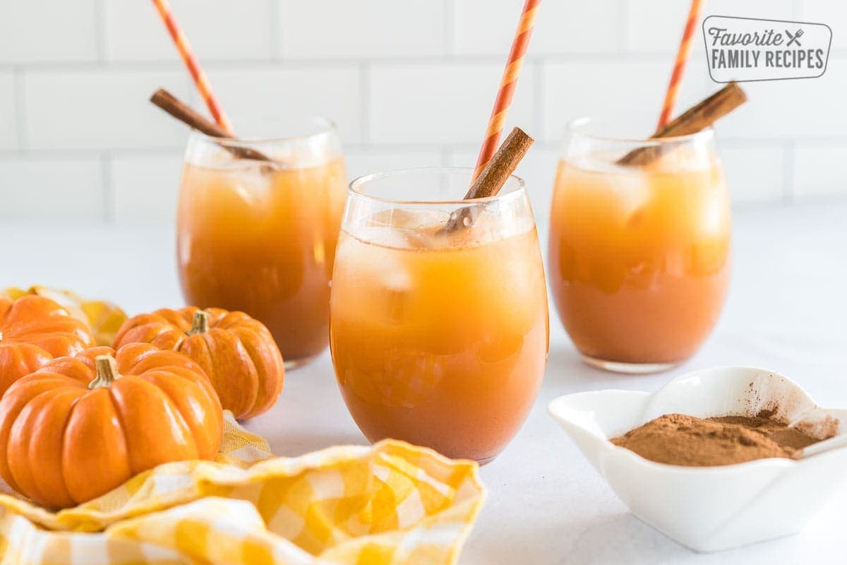 A glass of pumpkin juice topped with a cinnamon stick and a straw