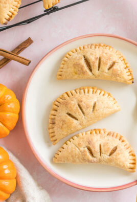 Three pumpkin pasties on a plate with a gold fork