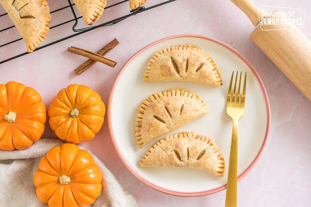 Three pumpkin pasties on a plate with a gold fork.