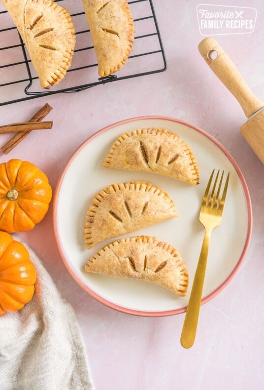 Three pumpkin pasties on a plate with a gold fork