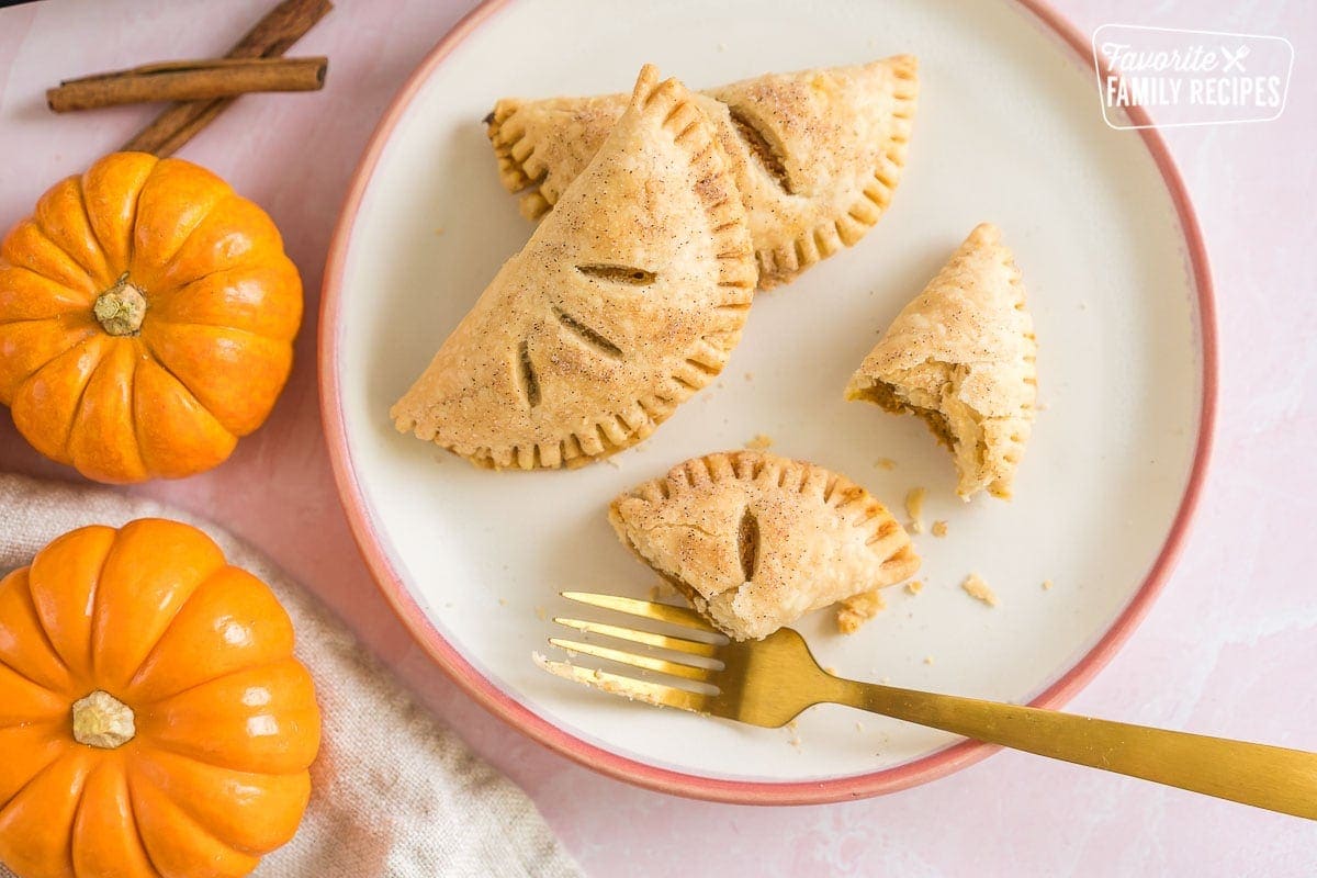 Three pumpkin pasties on a plate with a gold fork.