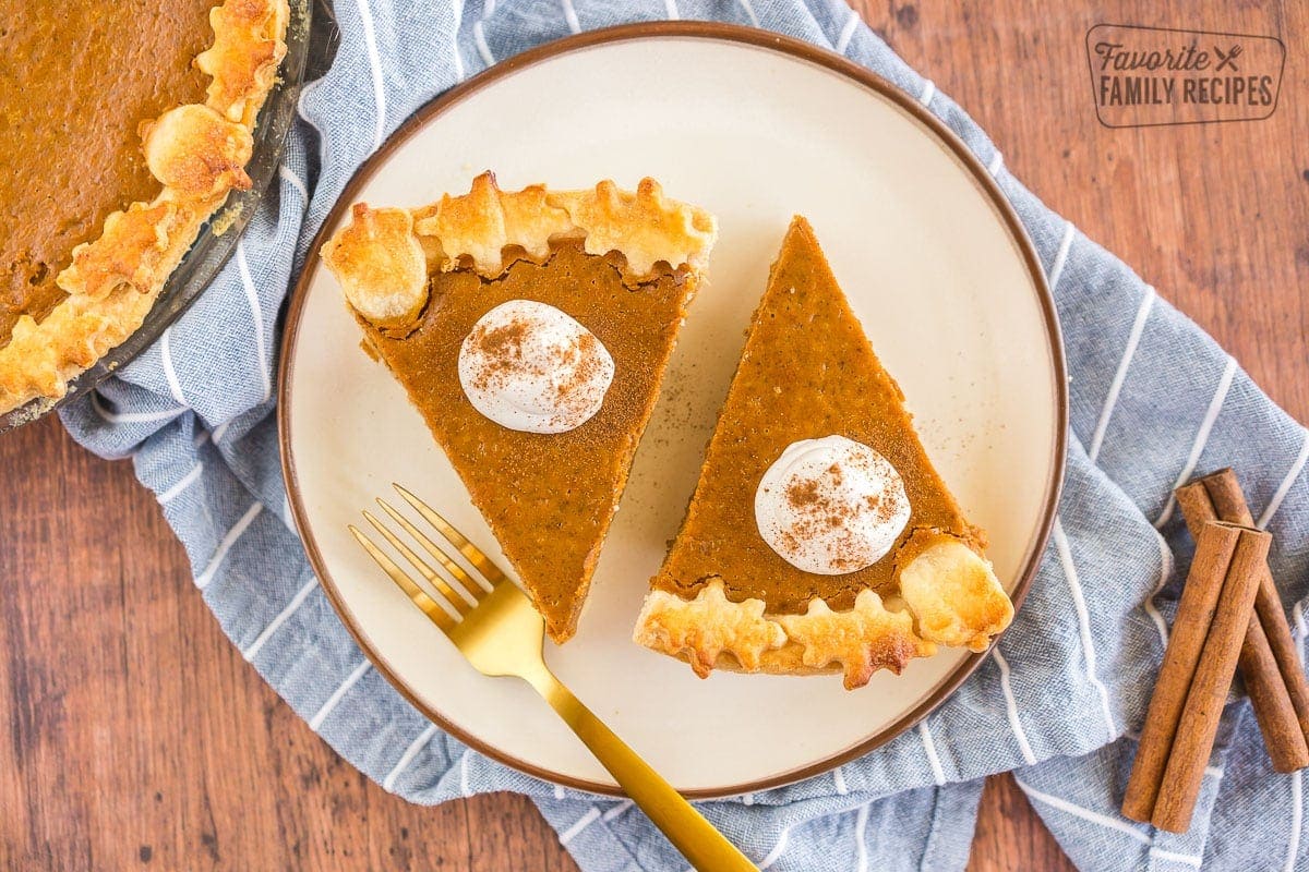 Two slices of pumpkin pie topped with whipped cream and cinnamon.