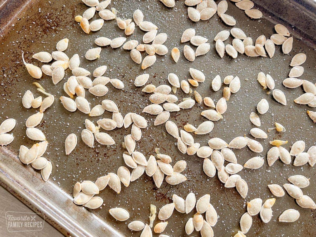 Raw pumpkin seeds on a baking sheet with salt