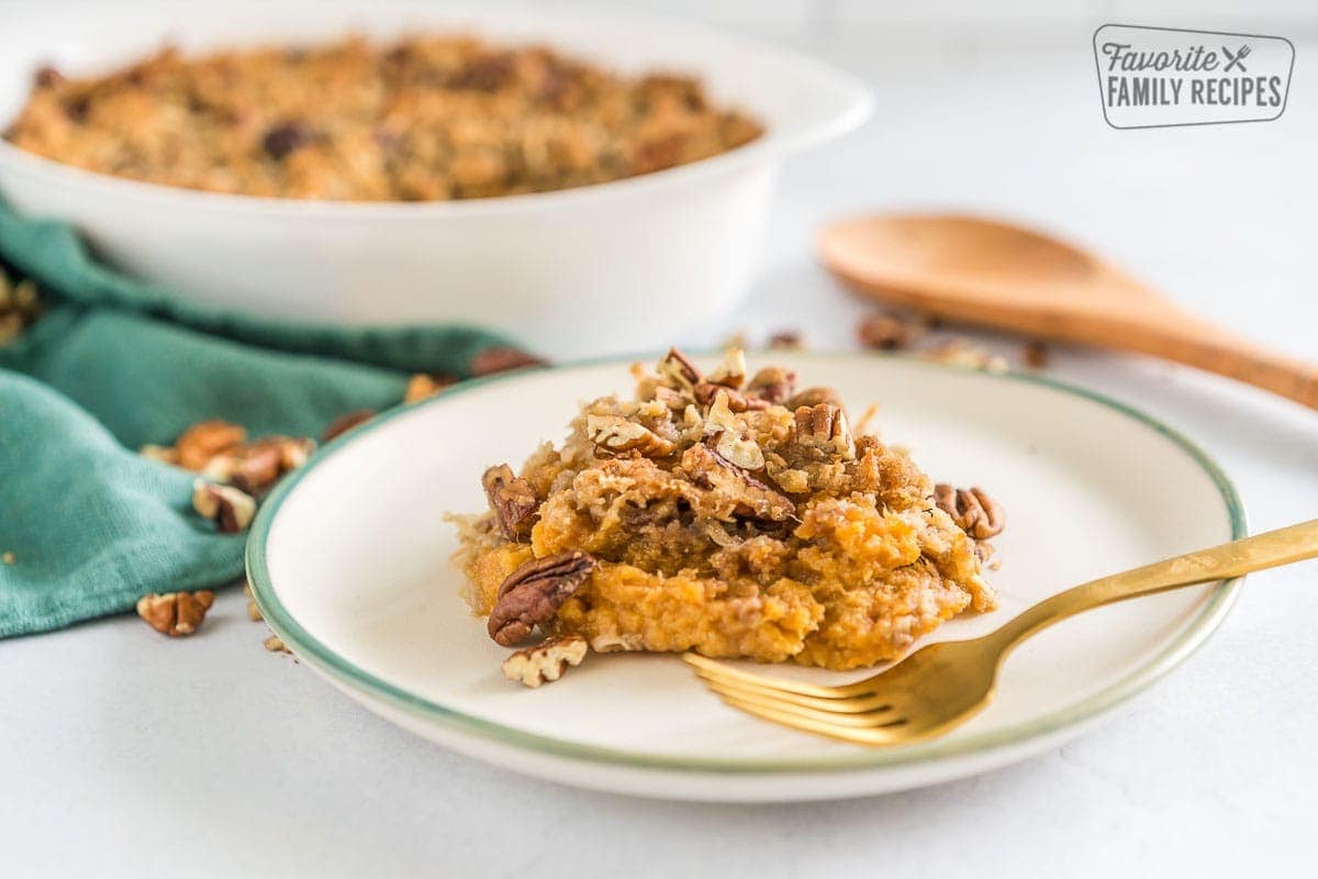 A scoop of sweet potato casserole on a plate with a gold fork.