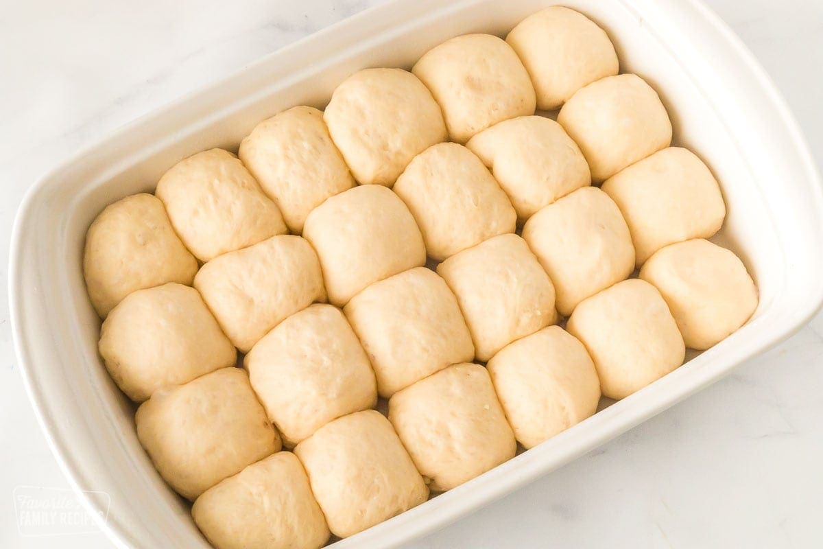 Uncooked dinner rolls that have risen in a pan