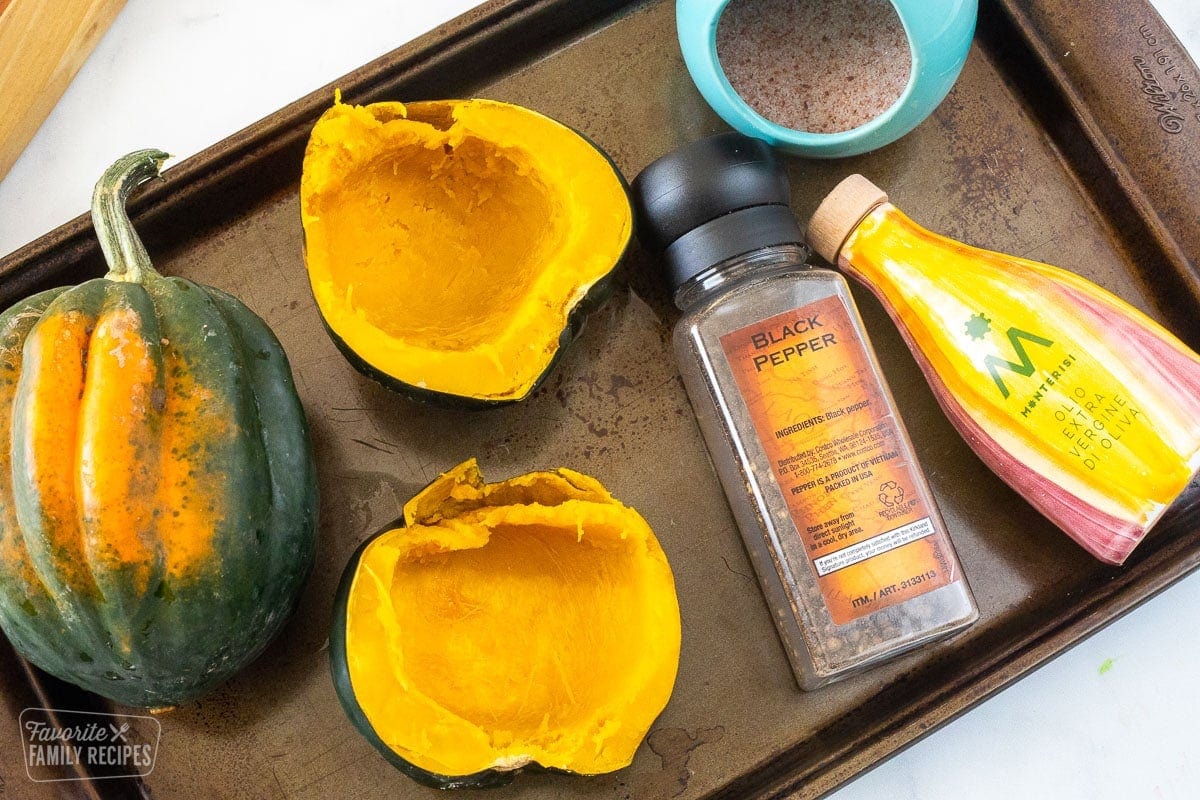 Acorn squash on a baking sheet with seasonings.