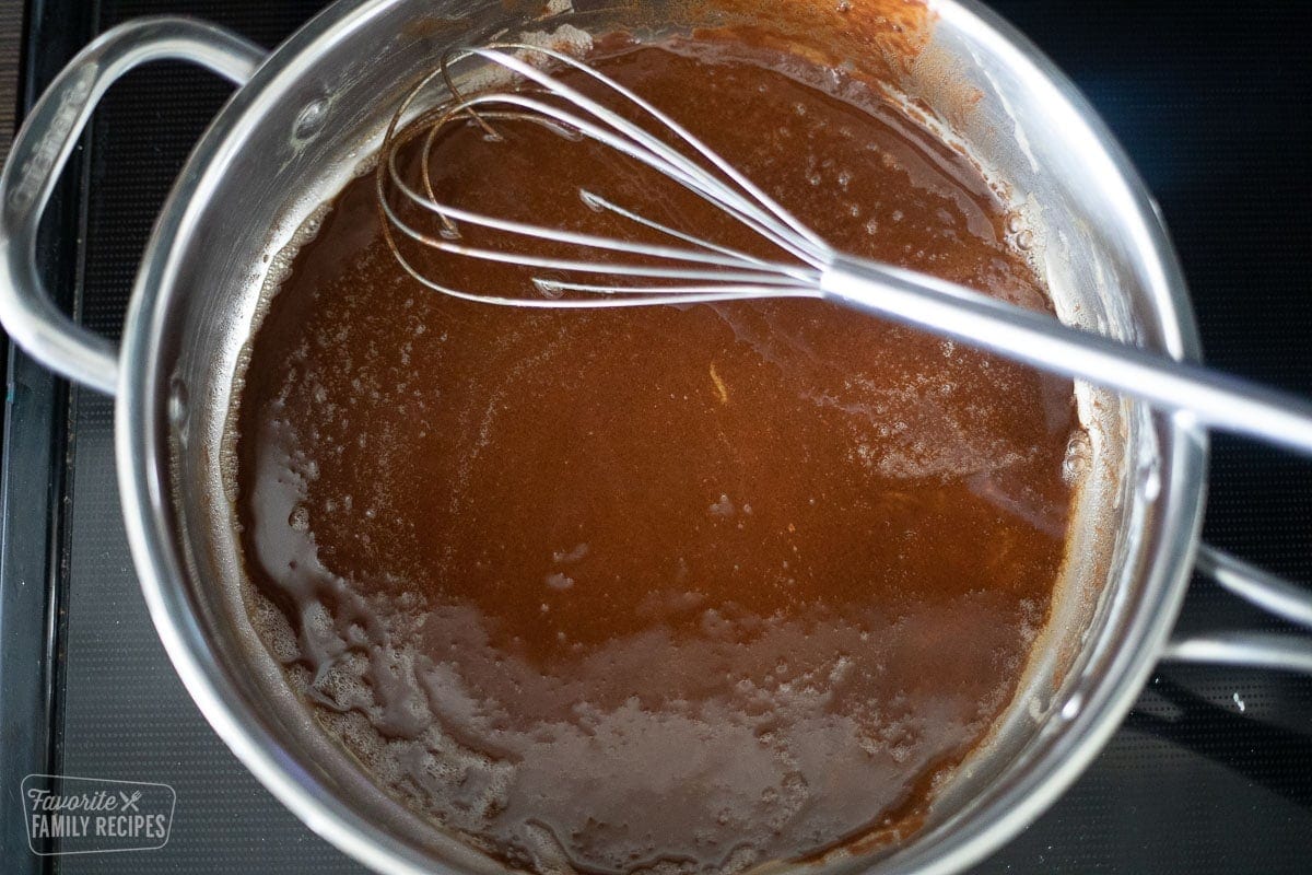Dark brown gravy in a skillet on the stovetop with a whisk