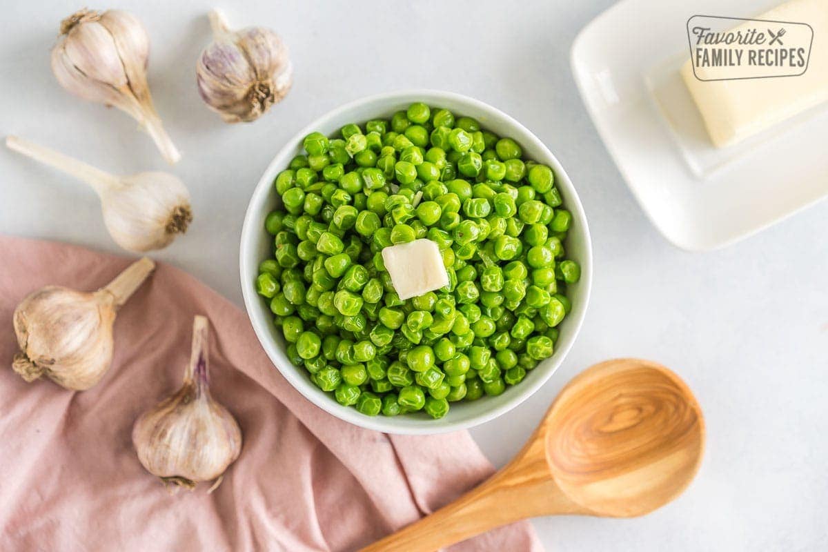 Green cooked frozen peas in a bowl topped with butter