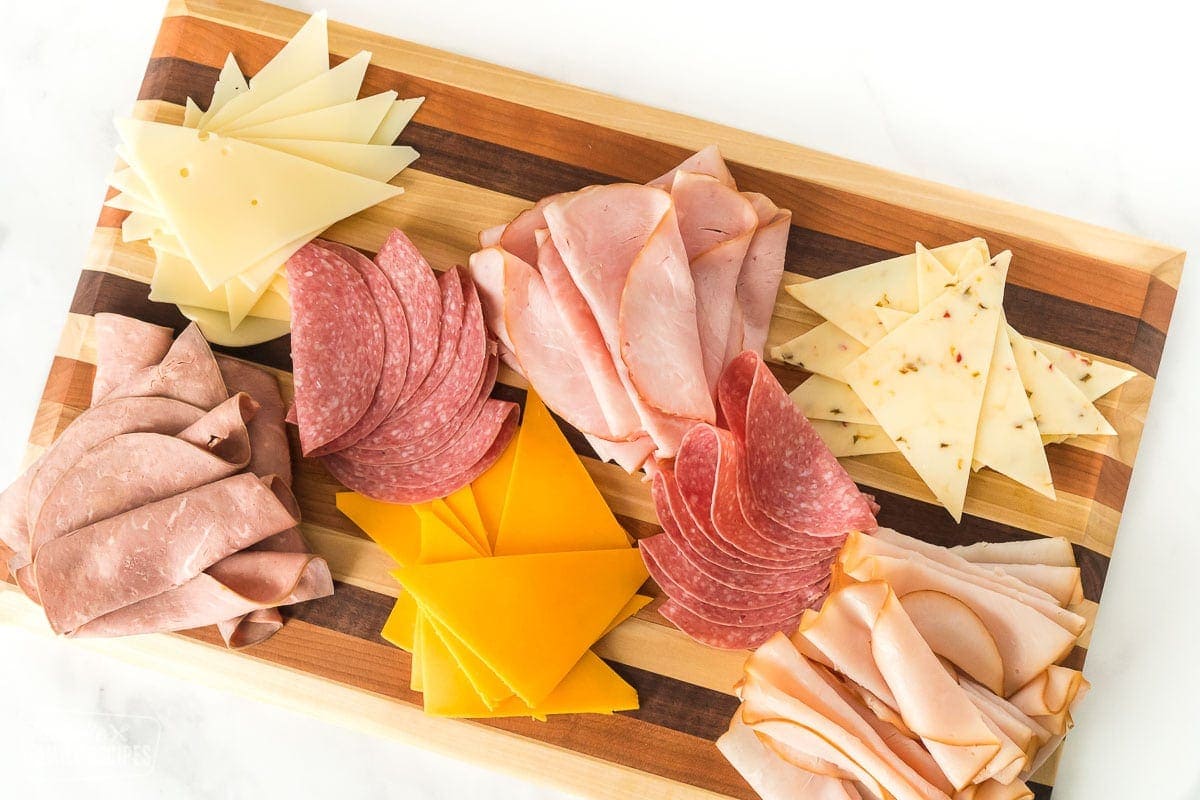 Deli meats and sliced cheeses on a cutting board.