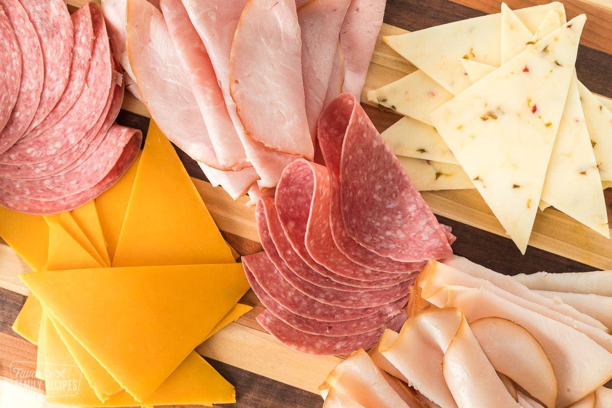 A close up of deli meats and cheeses on a tray.