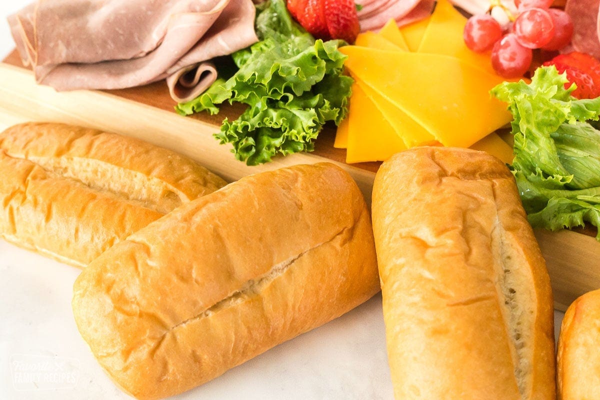 Sub rolls in front of a deli tray.