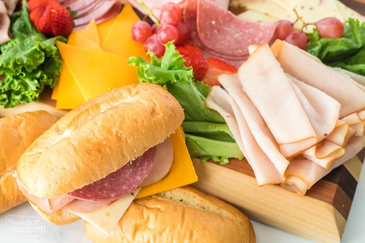 A deli sandwich on a meat and cheese tray.