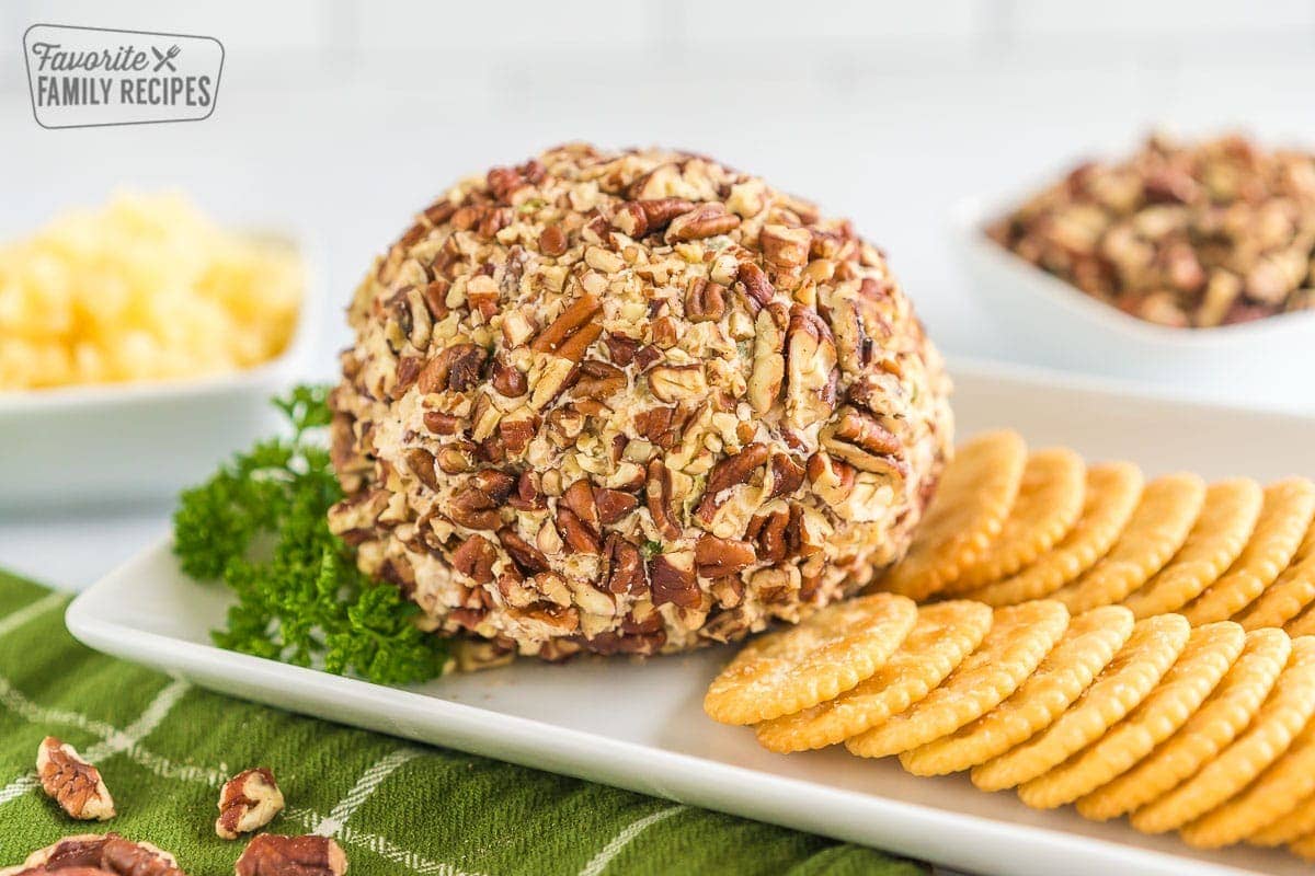 A pineapple cheese ball on a platter with crackers.