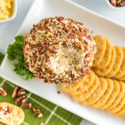 A cheese ball with some scooped out on a platter with crackers