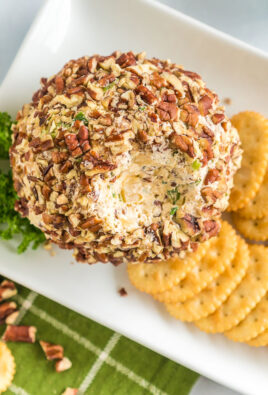 A cheese ball with some scooped out on a platter with crackers