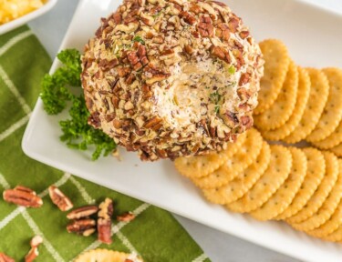 Pineapple cheese ball on a platter with crackers