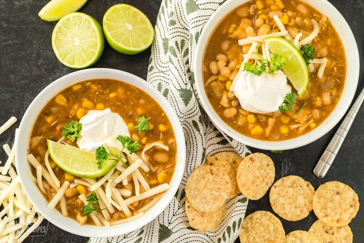 Two bowls of white chicken chili with white beans, chicken, Jack cheese, and sour cream.