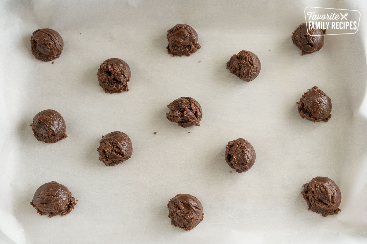 Andes mint cookie dough rolled into balls on parchment paper.