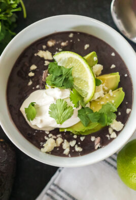 Black bean soup on a table with avocados and a lime