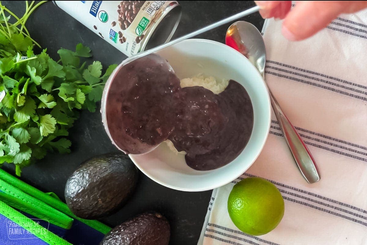 Black bean soup being poured into a bowl with a ladle