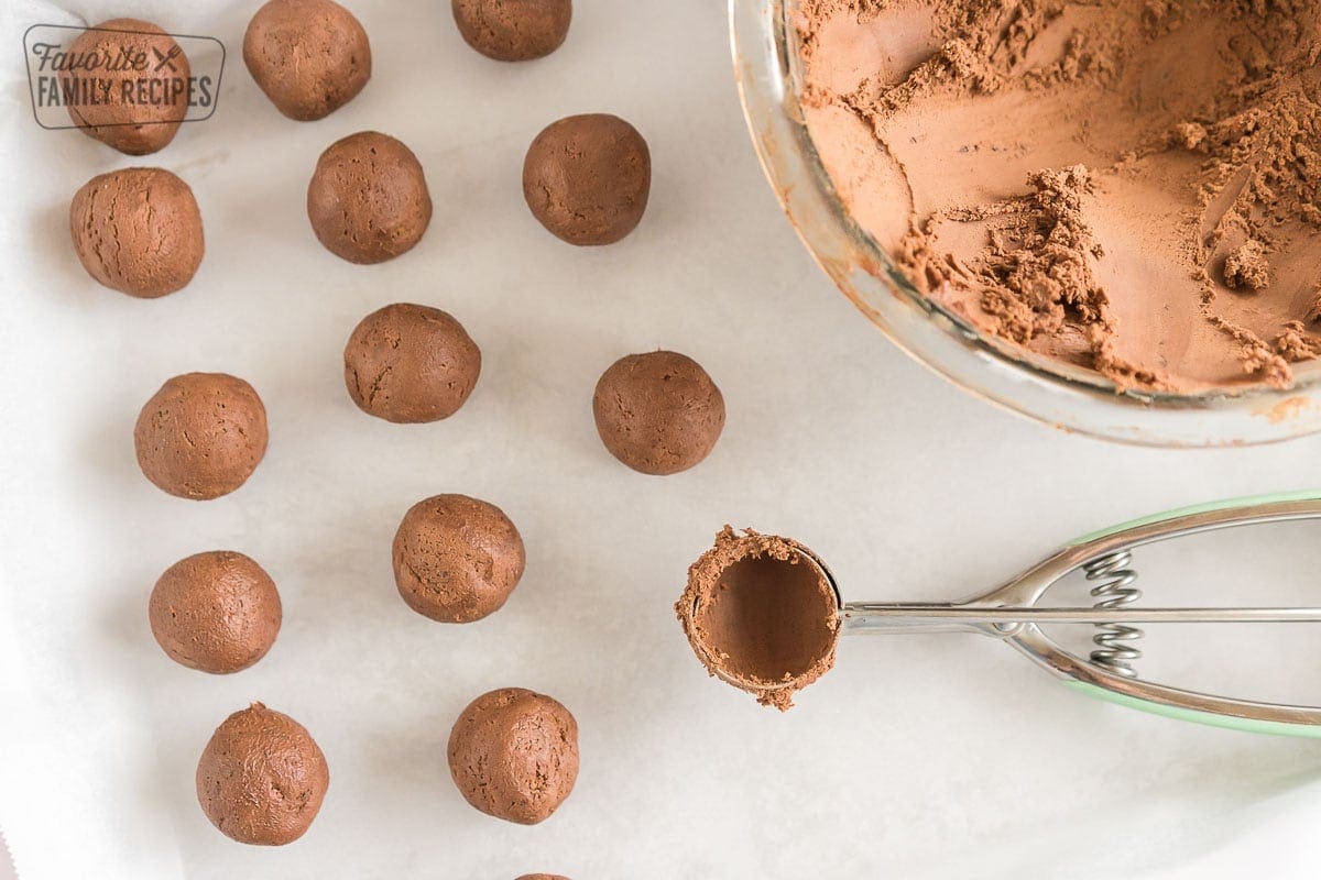 A baking sheet with rolled truffles and a scoop