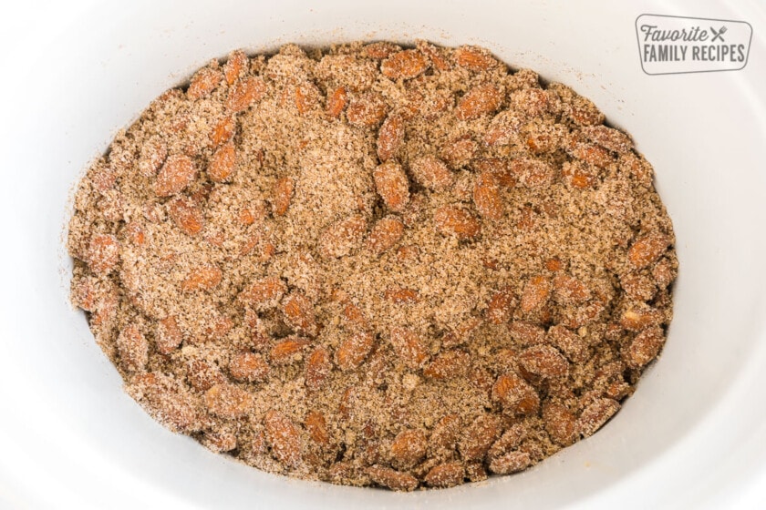 A crock pot full of almonds, cinnamon, and sugar