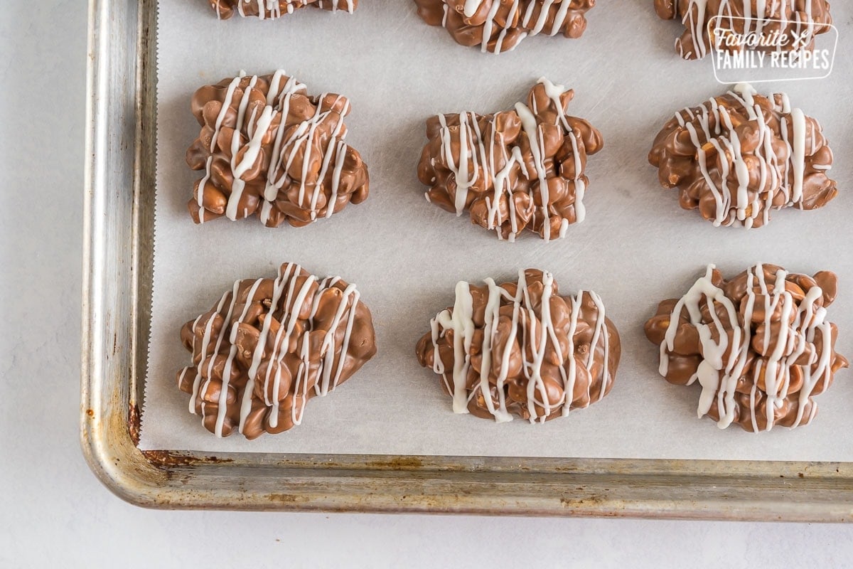 Peanut Clusters drizzled with white chocolate on a baking pan