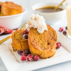 Eggnog French Toast on a plate with sugared cranberries and whipped cream