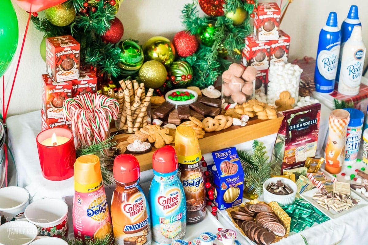 Coffee creamers, candies, cookies, candy canes, hot cocoa bombs, and other treats on a table