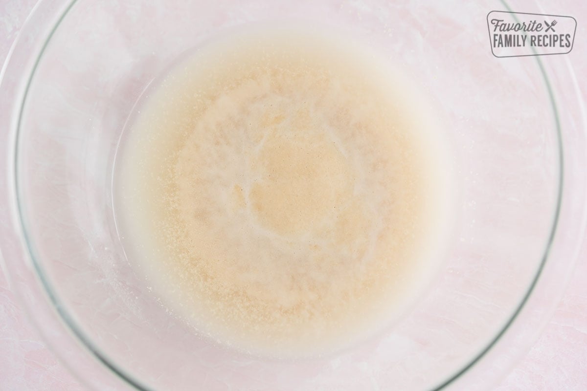 Water, sugar, and yeast combined in a bowl