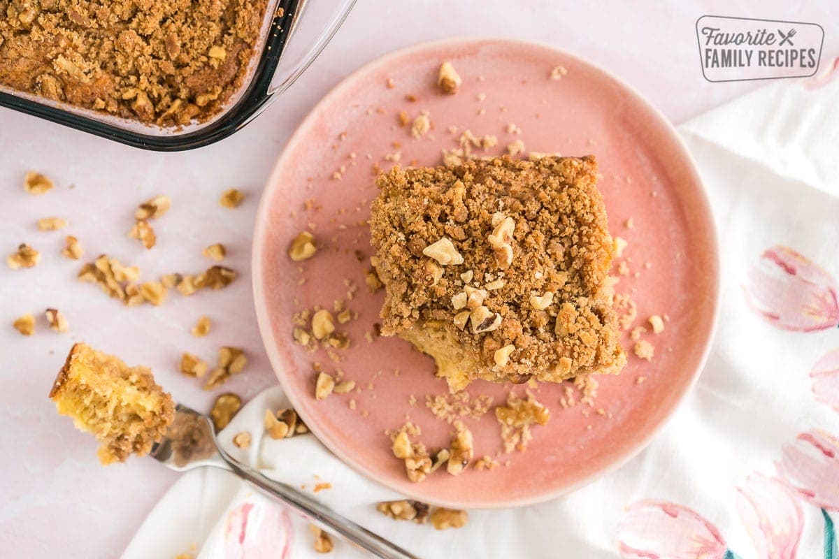 A piece of coffee cake on a pink plate with a bite taken out.