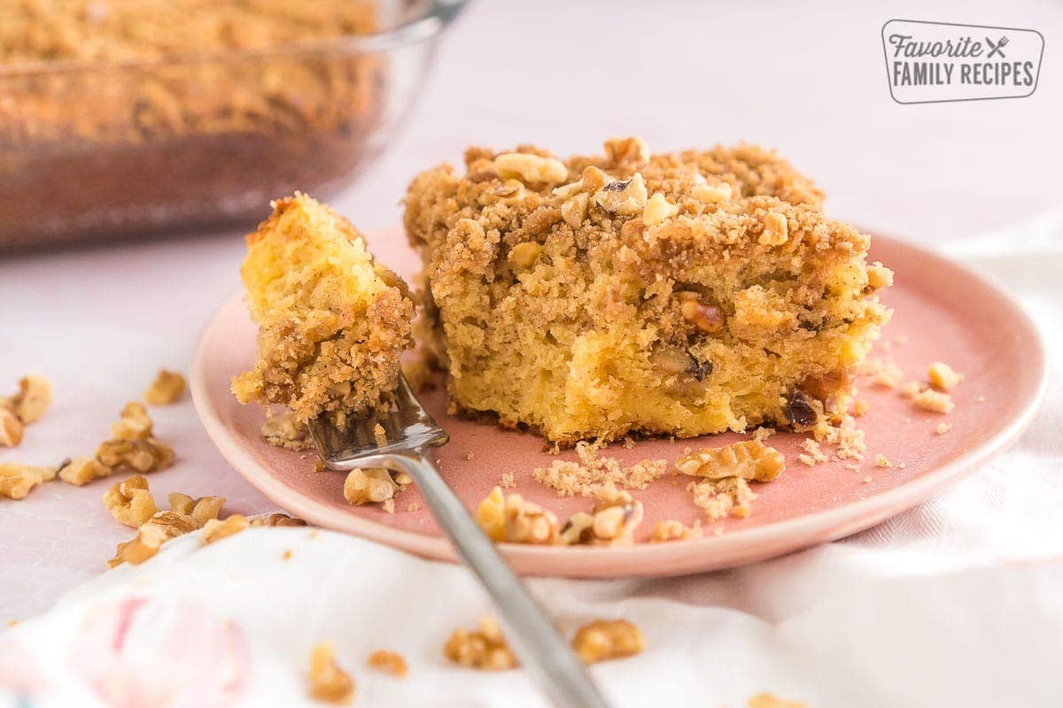 A piece of coffee cake on a pink plate with a bite taken out.