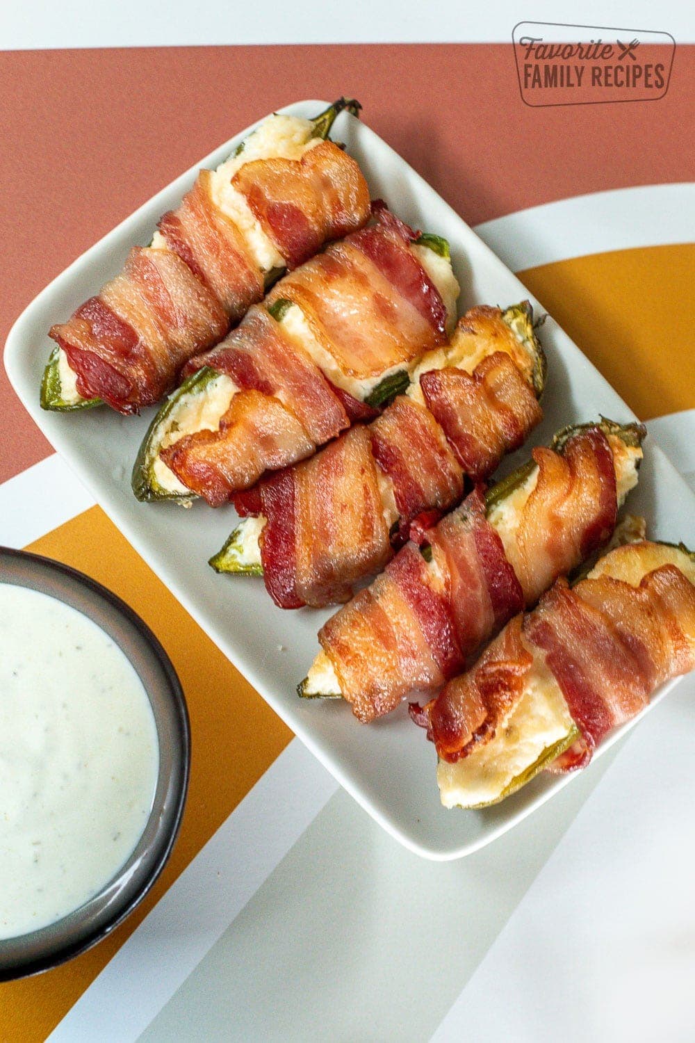 Bacon Wrapped Jalapeños poppers on a plate with a side of ranch